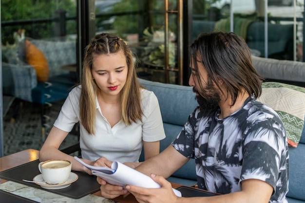 Foto jonge man met notitieboekje en praten met zijn vriendin in het restaurant