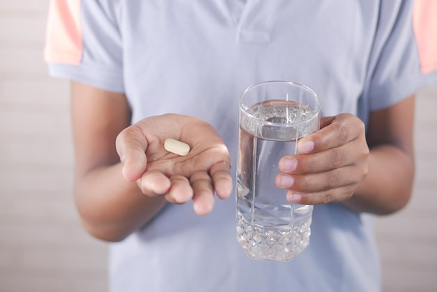 jonge man met pillen en glas water met kopie ruimte