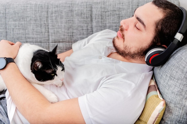 Jonge man met pluizige kat liggend op een bank