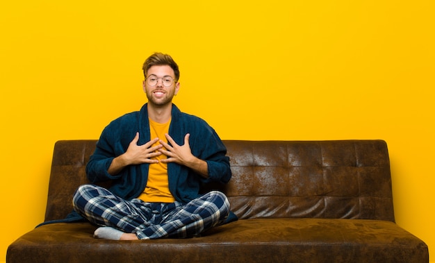 Jonge man met pyjama op zoek blij, verrast, trots en opgewonden, wijzend naar zichzelf