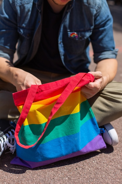 Jonge man met regenboog herbruikbare tas zit op de stoep