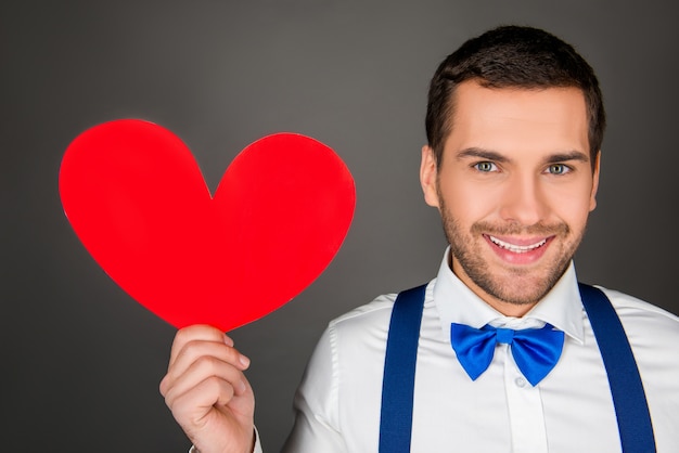 Foto jonge man met rood papier hart