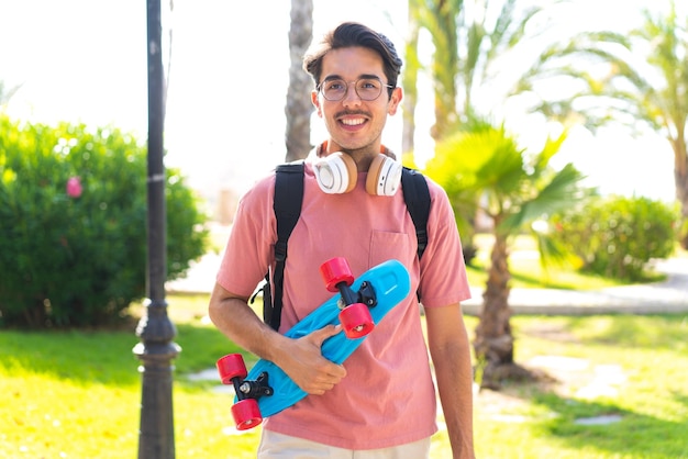 Jonge man met skate in de buitenlucht met een gelukkige uitdrukking