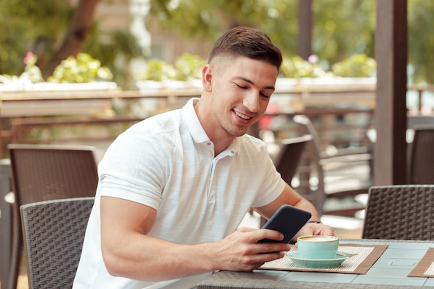 Jonge man met smartphone in café