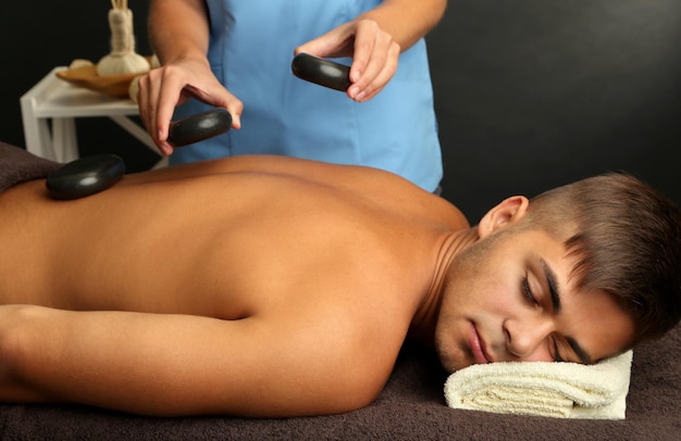 Jonge man met stenen massage in spa salon