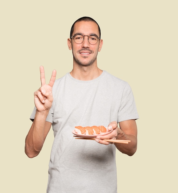 Jonge man met stokjes om sushi te eten