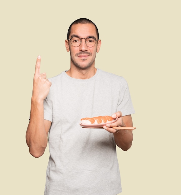 Jonge man met stokjes om sushi te eten