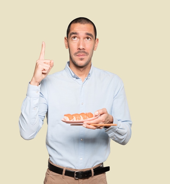 Jonge man met stokjes om sushi te eten