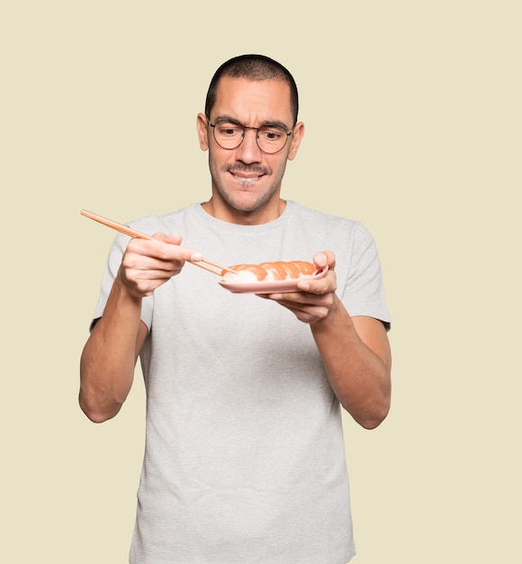 Jonge man met stokjes om sushi te eten