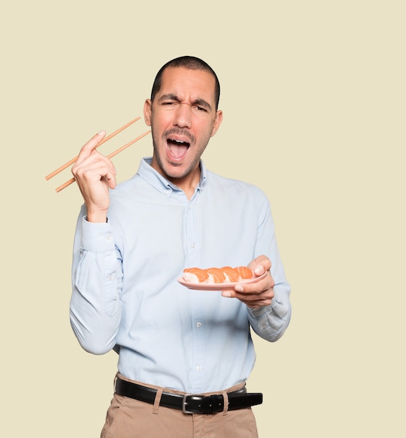 Jonge man met stokjes om sushi te eten