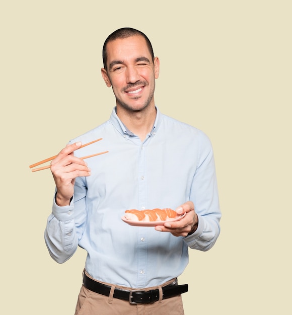 Jonge man met stokjes om sushi te eten