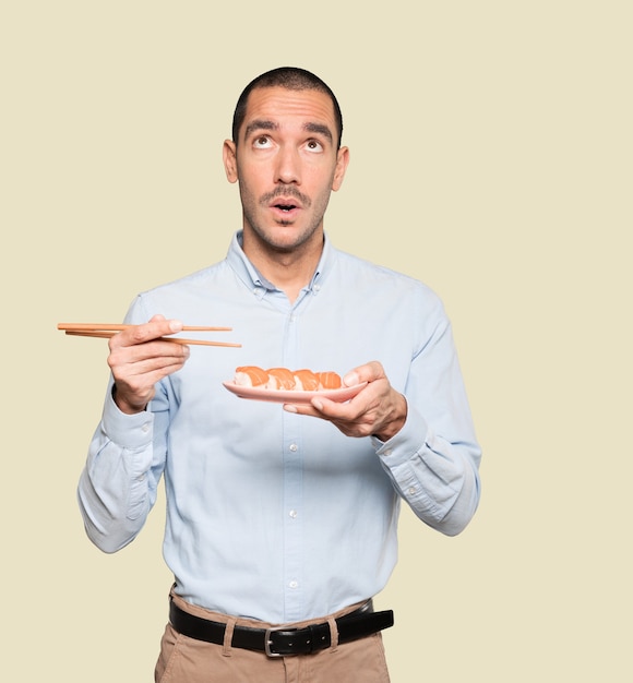 Jonge man met stokjes om sushi te eten