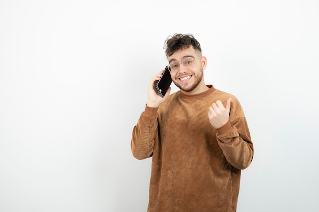 jonge man met telefoontje over witte muur.