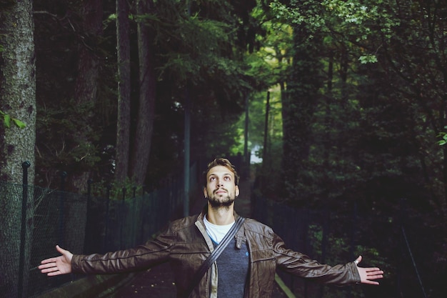 Foto jonge man met uitgestrekte armen in het bos.