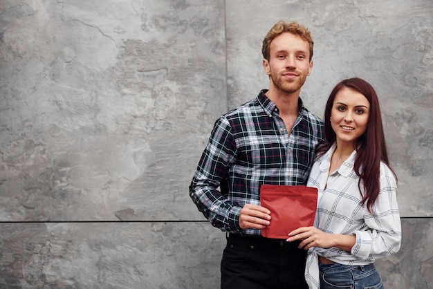 Jonge man met vrouw die samen staat en een rood pakje koffie vasthoudt