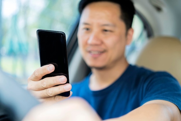 Jonge man met zijn smartphone achter het stuur