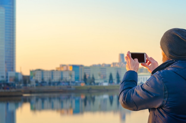 Jonge man neemt foto's van de stad op een smartphone