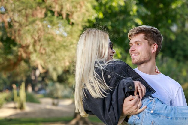 Jonge man neemt zijn vriendin op schoot en lacht naar haar