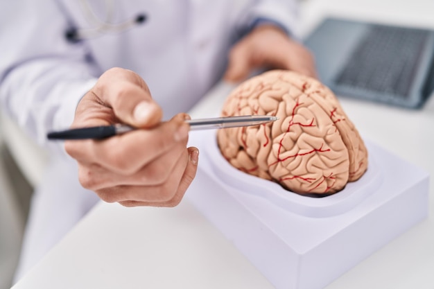 Foto jonge man neuroloog wijst naar hersenen die in de kliniek werken