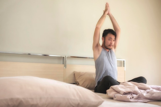 Foto jonge man oefent terwijl hij op bed zit in de slaapkamer