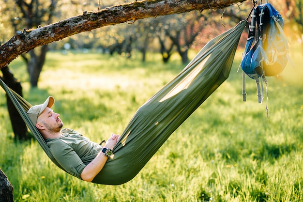 Jonge man ontspannen in een hangmat in zonnige zomer park