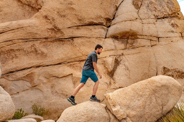 Foto jonge man op de top van joshua tree rocks voelt zich vrij in het verbazingwekkende landschap