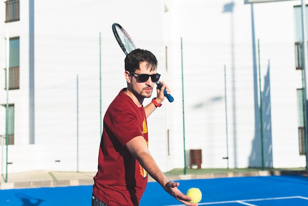 Jonge man op het punt om de tennisbal met het racket te raken.