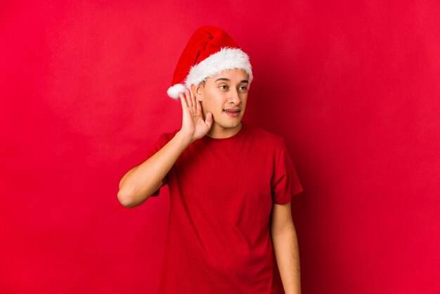 Jonge man op kerstdag probeert te luisteren naar een roddel.