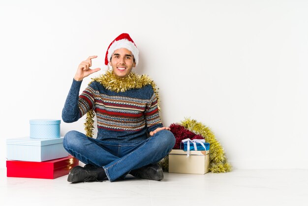 Jonge man op kerstdag verhogen beide duimen omhoog, glimlachen en zelfverzekerd.