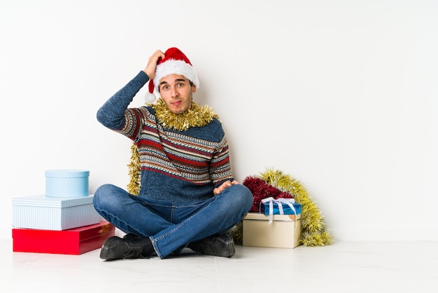 Jonge man op kerstdag wijzende tempel met vinger, denken, gericht op een taak.