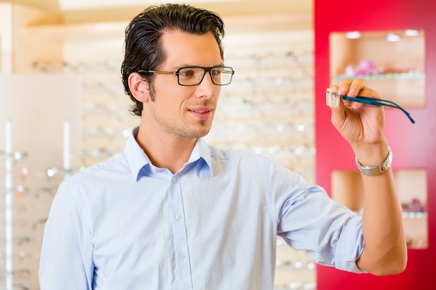 Jonge man op opticien met een bril