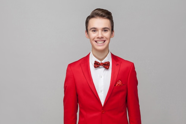 Jonge man op rode jas staande op grijze achtergrond