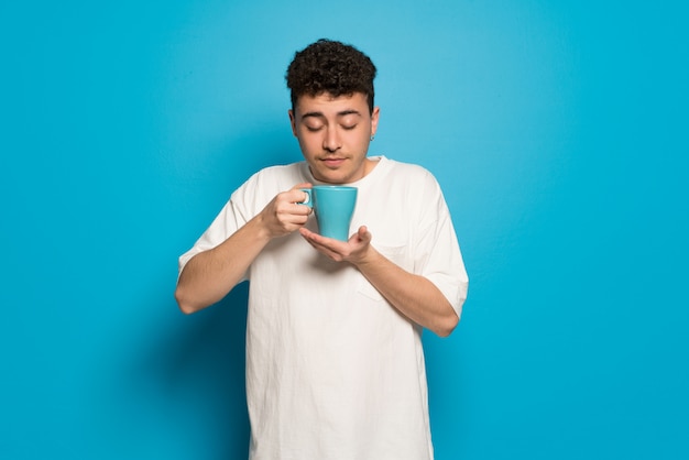 Jonge man over blauw met een warme kop koffie