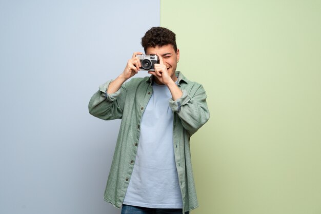 Jonge man over blauwe en groene muur met een camera