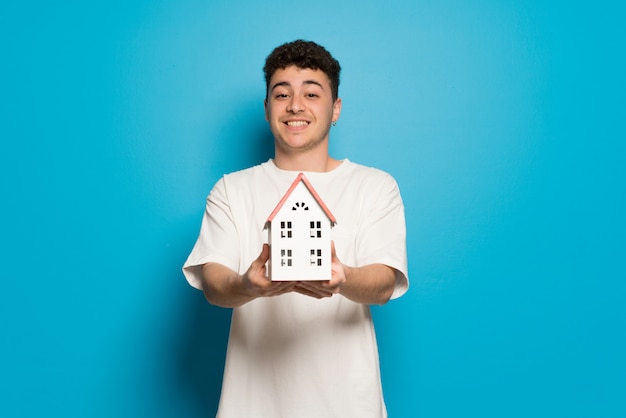 Jonge man over blauwe muur met een klein huis