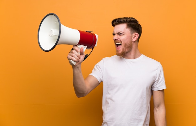 Jonge man over geïsoleerde achtergrond schreeuwen met een megafoon