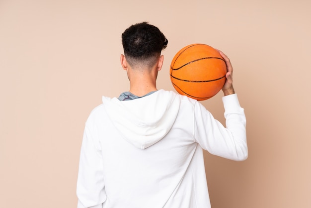 Jonge man over geïsoleerde spelen basketbal in achterste positie