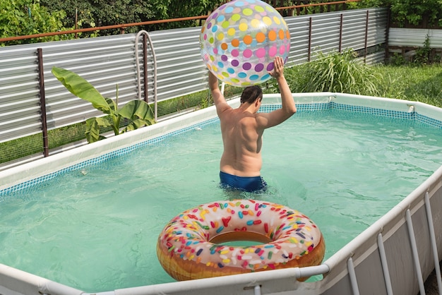 Jonge man plezier bij het zwembad met springkussens