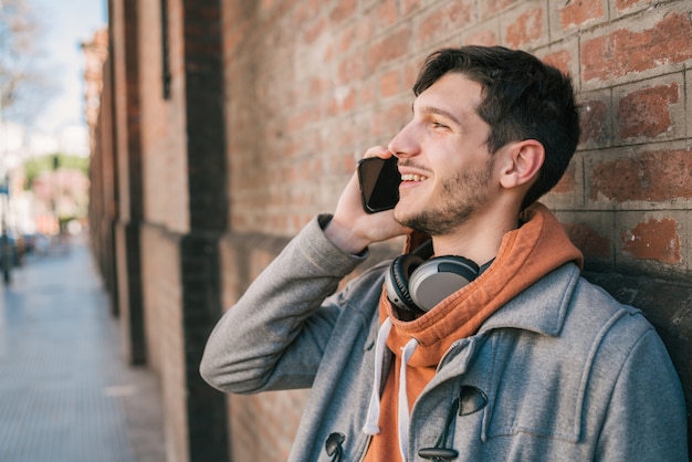 Jonge man praten aan de telefoon buitenshuis.