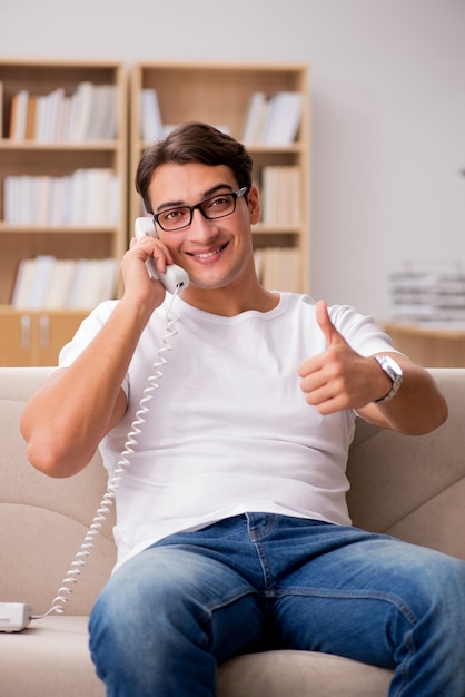 Jonge man praten aan de telefoon liggend in bank