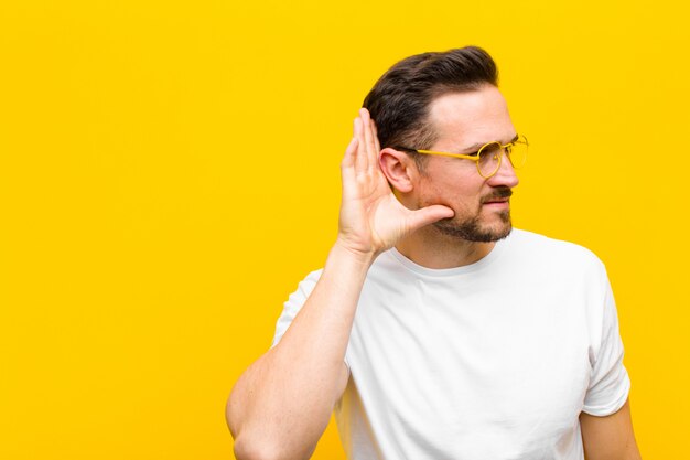 Jonge man probeert een geheim gesprek of roddel te horen