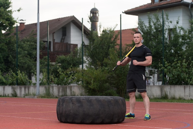 Jonge man raakt band - Buiten trainen met hamer en tractorband