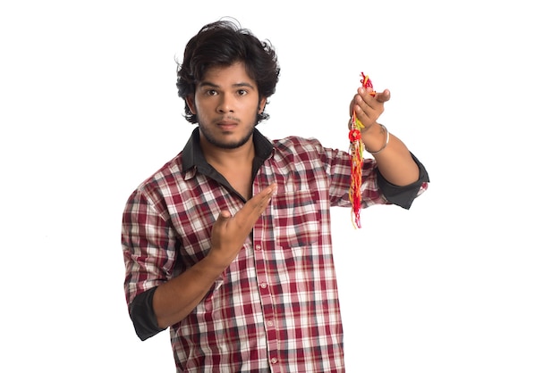 Jonge man rakhi in de hand tonen en uitdrukking geven aan een gelegenheid van Raksha Bandhan festival.