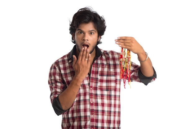 Jonge man rakhi in de hand tonen en uitdrukking geven aan een gelegenheid van Raksha Bandhan festival.