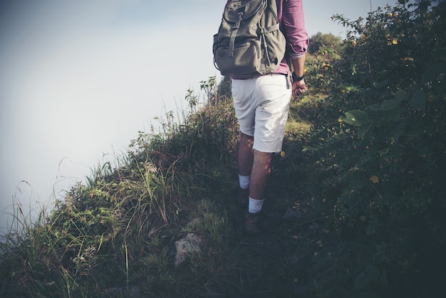 Jonge man reiziger met rugzak ontspannen buiten met rotsachtige bergen op achtergrond zomervakanties en lifestyle wandelen concept.