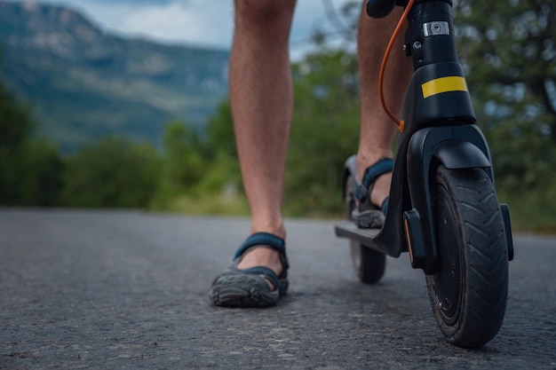 Jonge man rijdt op een elektrische scooter op de bergketen Ecologisch transportconcept