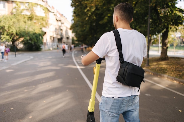 Jonge man rijdt op een elektrische scooter op een ecologisch transportconcept voor een vergadering, knappe man