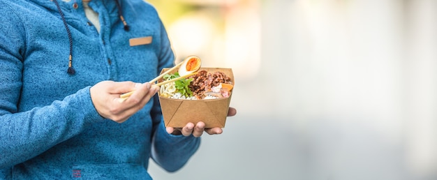 Jonge man's handen met lunch in een doos met gerecycled papier.