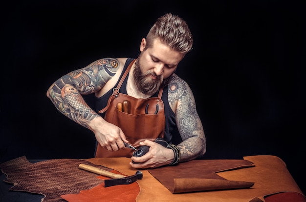 Foto jonge man, schoenmaker, oude handgemaakte schoen repareren in zijn atelier en kijken naar de camera