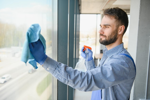 Jonge man schoonmaak raam in kantoor